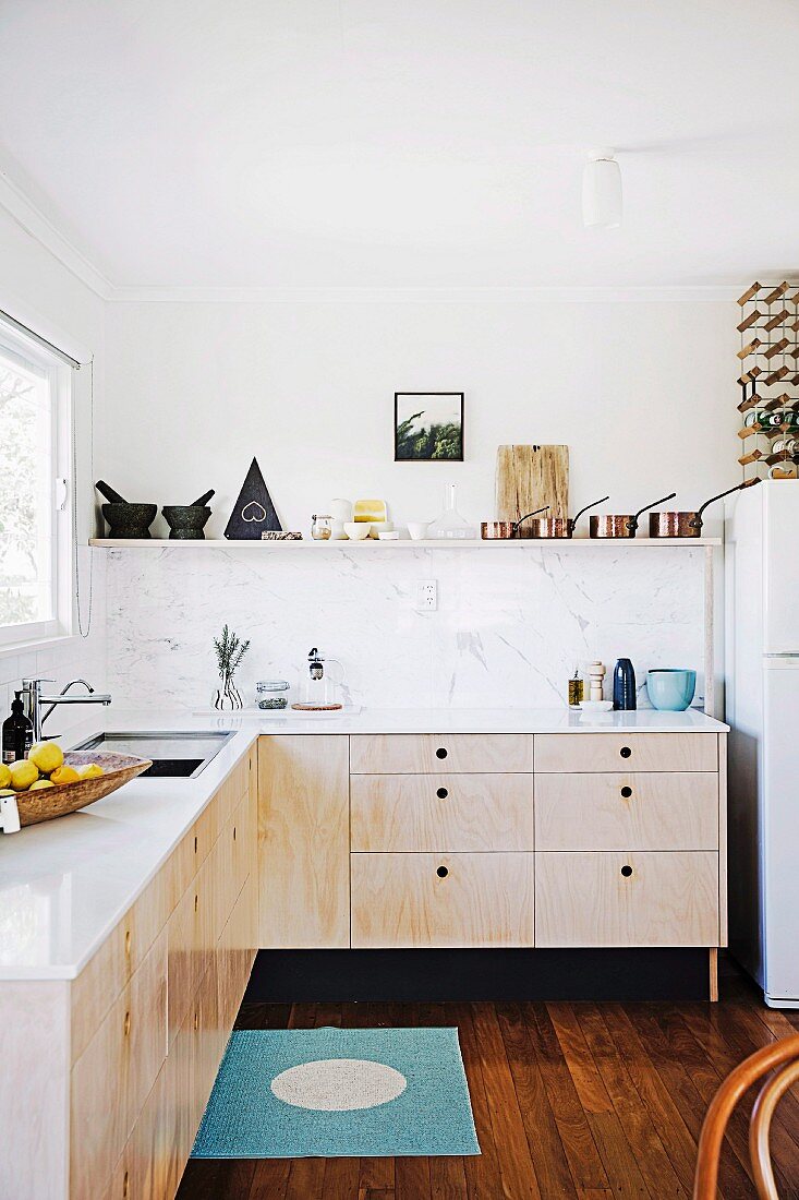 Modern, minimalist kitchen with wooden fronts and white worksurface