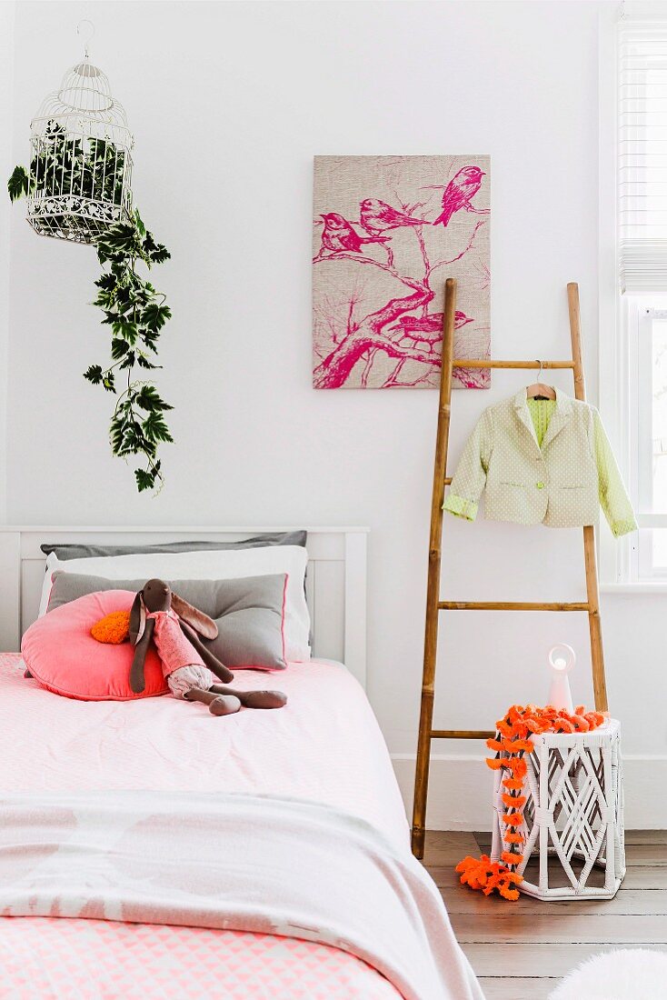 Bright, girl's bedroom with orange and pink accents and house plant in vintage birdcage