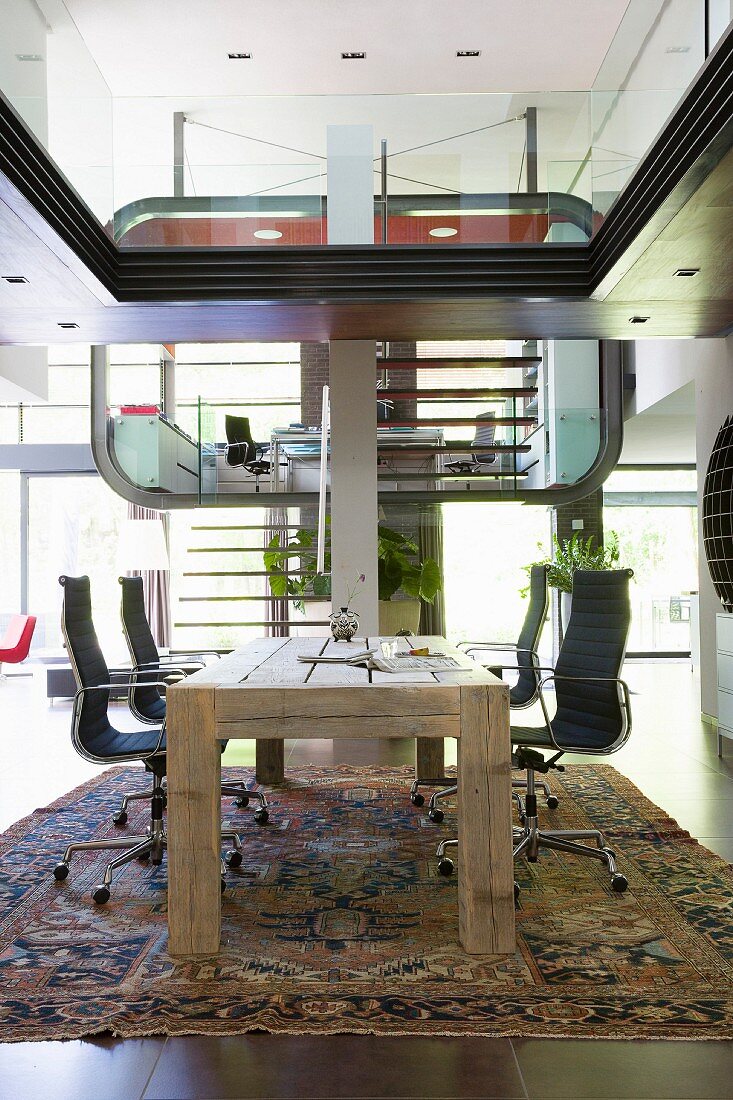 Futurist interior with study area in luxury apartment; rustic wooden table and Eames office chairs in foreround