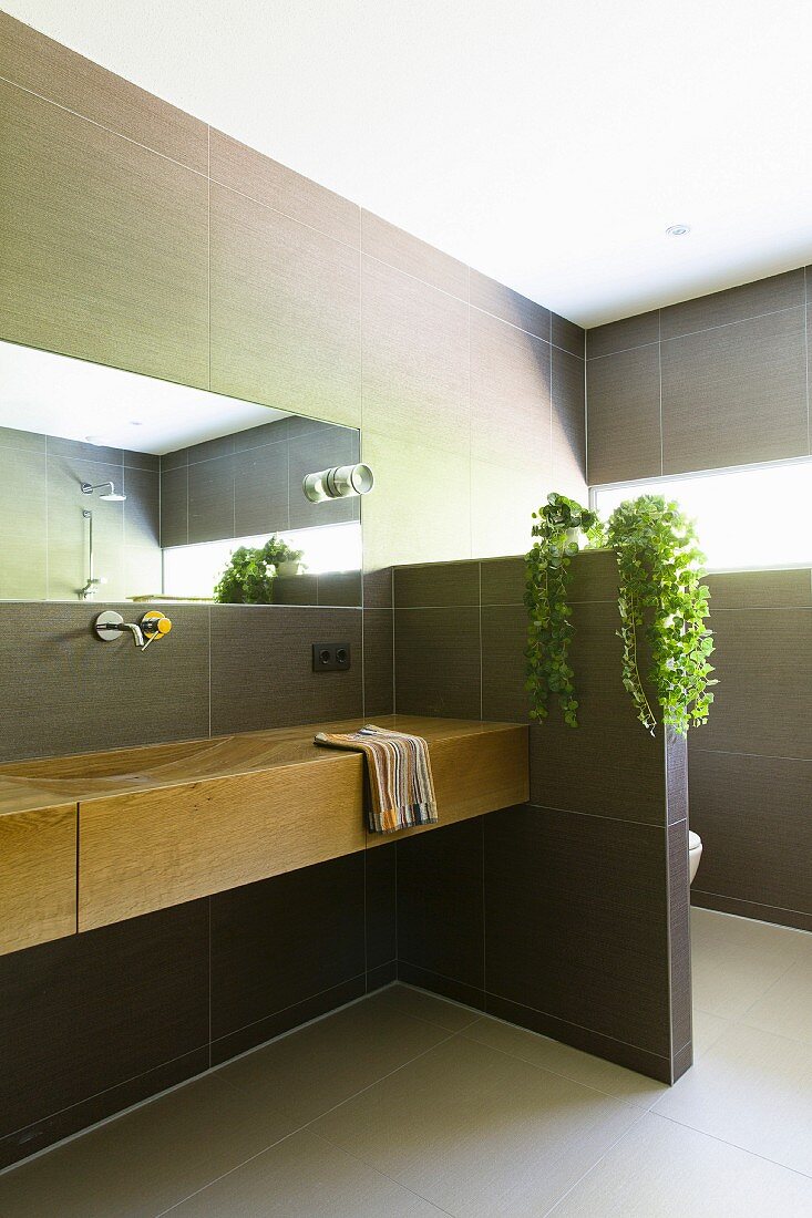 Modern tiled bathroom with elegant wooden washstand and partition screening toilet