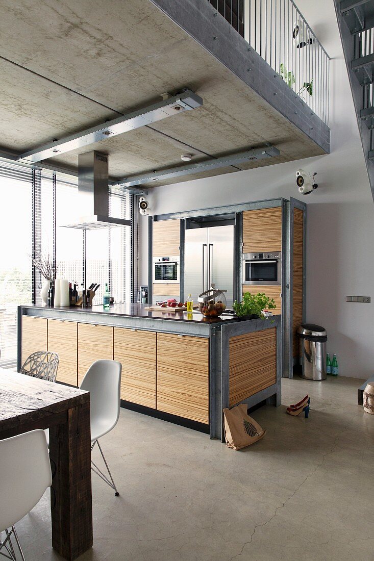 Modern kitchen area below gallery; counter and cupboards made from galvanised steel and zebrano veneer