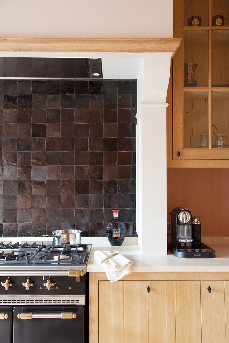 Gasherd vor dunklen Wandfliesen unter gemauertem Dunstabzug in Küchenzeile integriert
