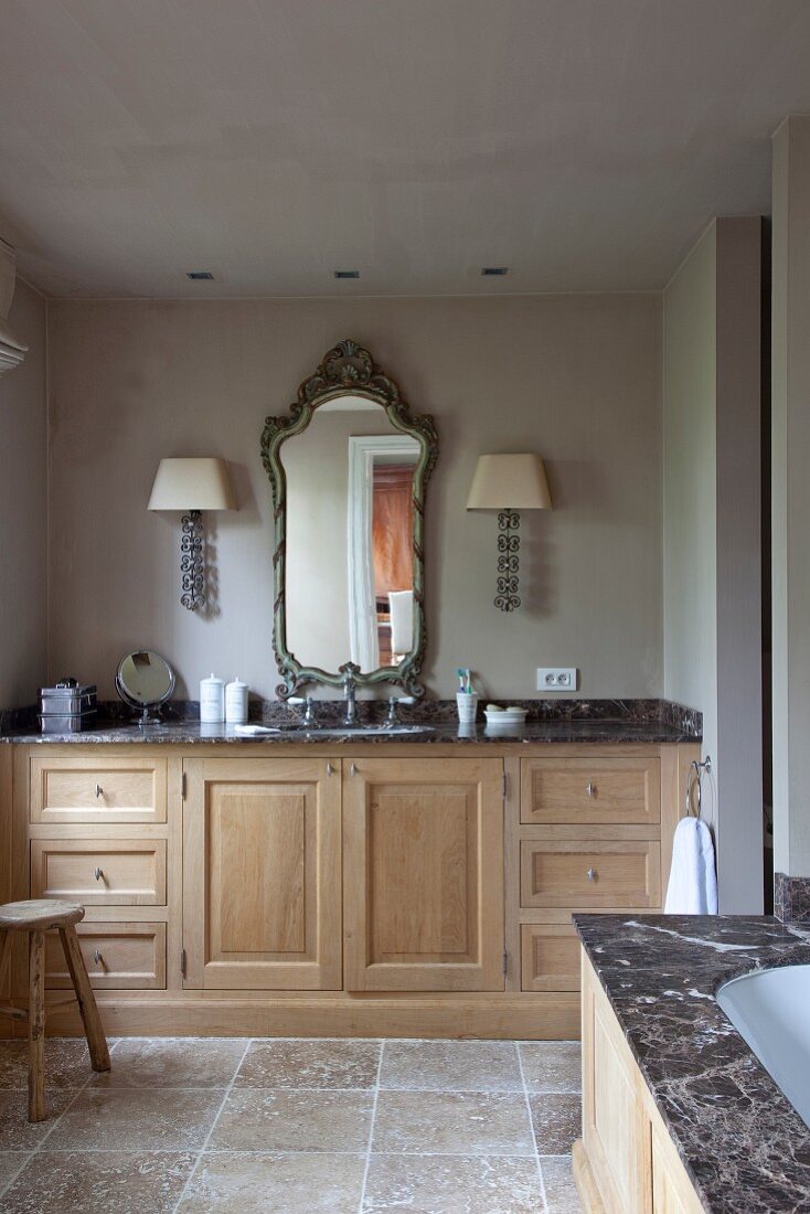 Custom washstand with marble worksurface and carved wooden base units in renovated bathroom