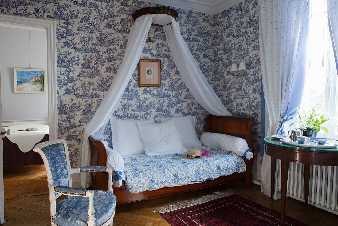 Antikes Schlittenbett mit Baldachin vor weiss-blauer Toile-De-Jouy Tapete