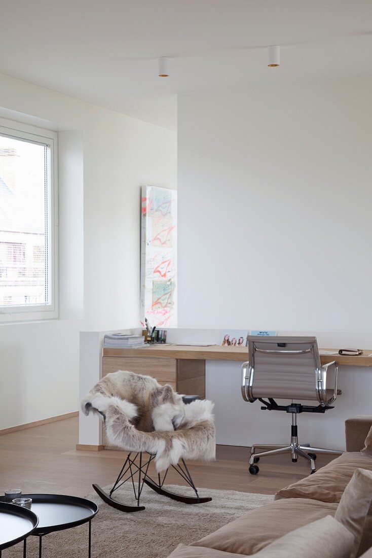 Custom, wooden modern desk, classic office chair, Eames rocking chair and fur blanket in comfortable lounge area