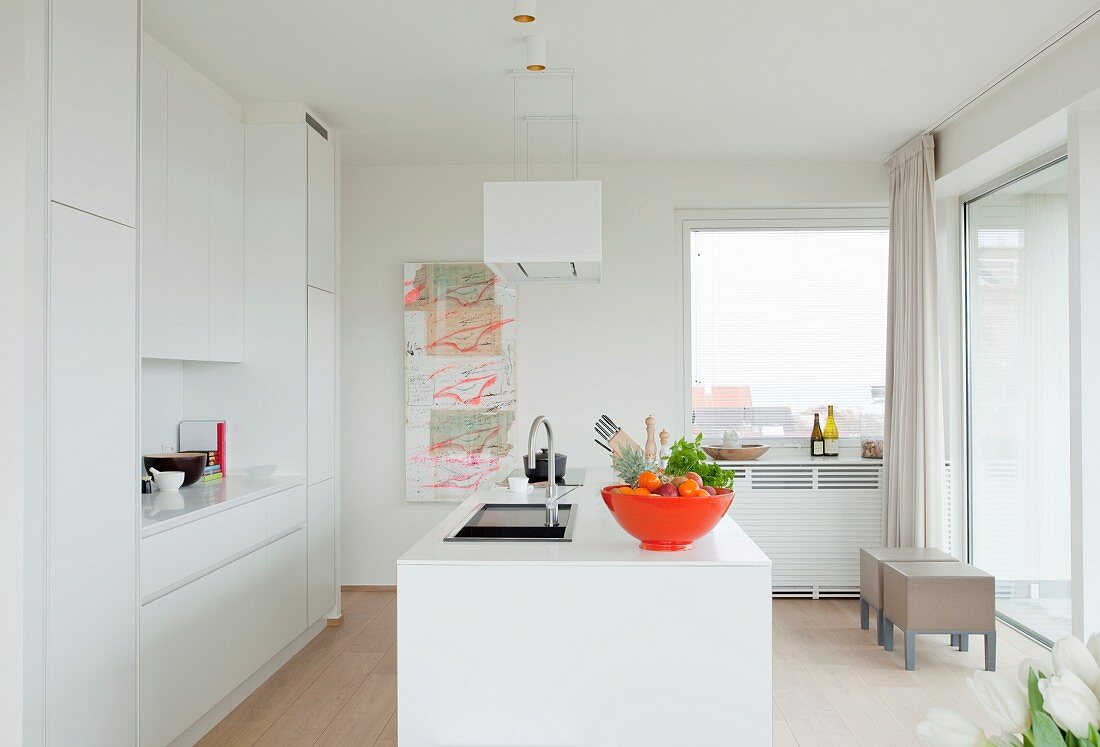 White Corian designer kitchen with island counter and orange fruit bowl