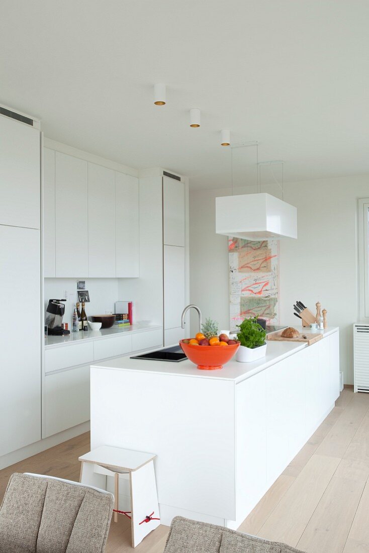 weiße Corian-Designerküche mit Küchentheke und orangefarbener Obstschale