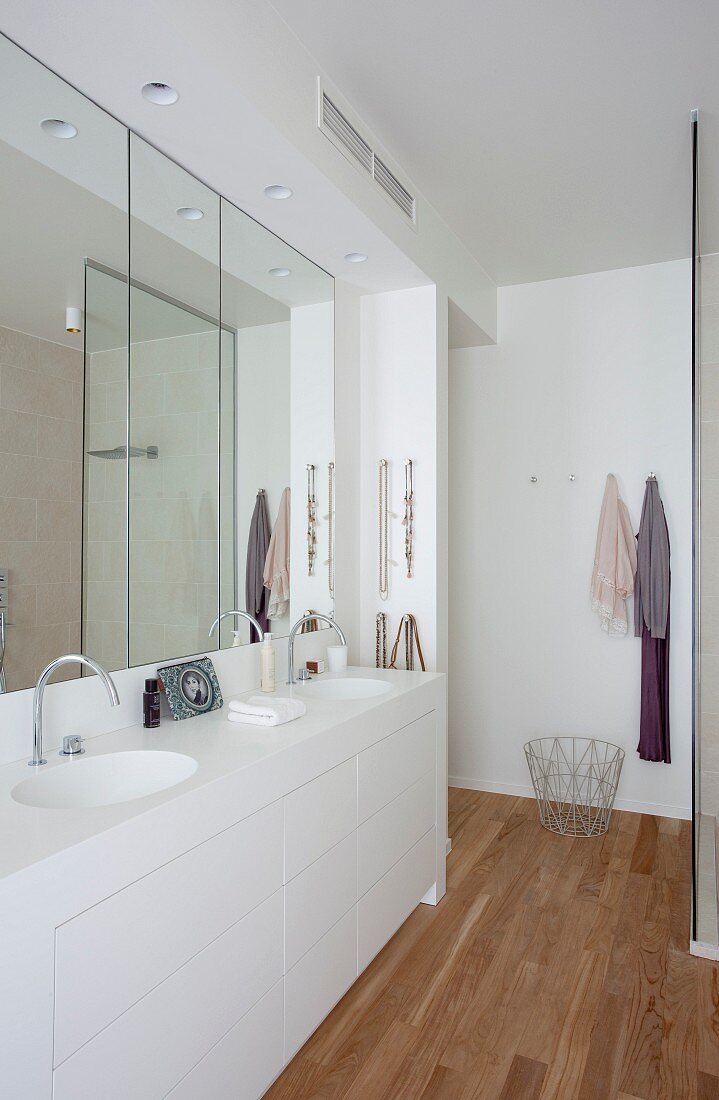 Elegantes weißes Bad mit maßgeferigtem Doppelwaschtisch, Wandspiegel und Teakholzparkett