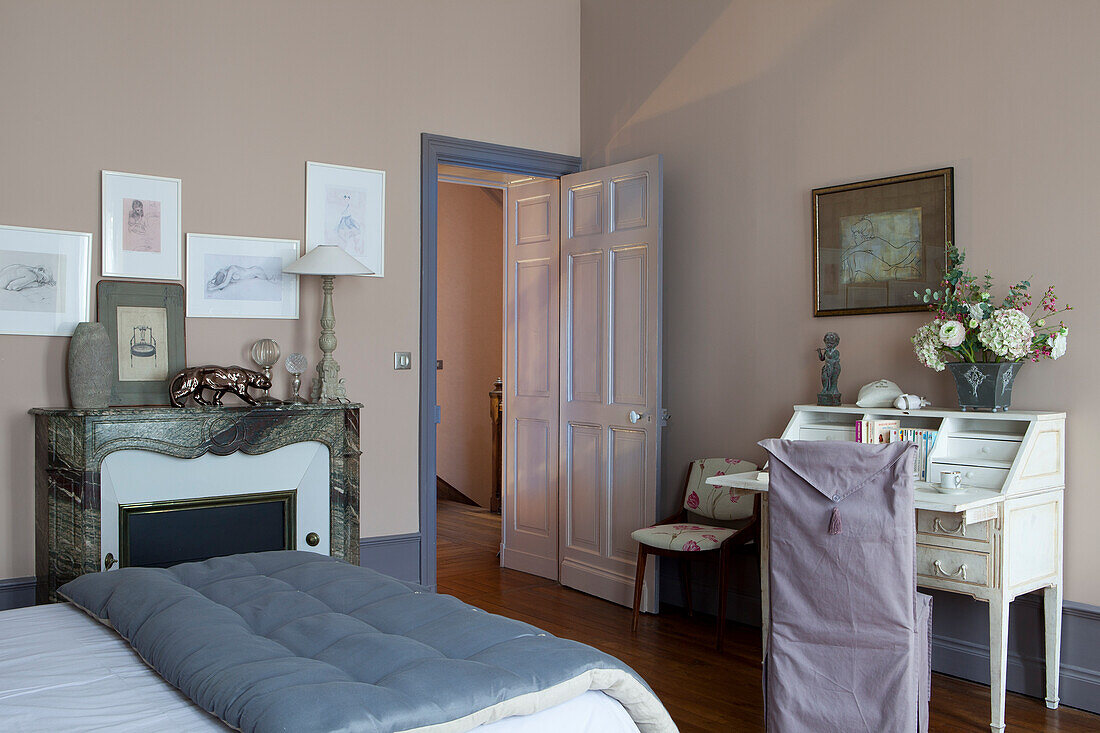 Chair with lilac loose cover and antique writing desk in elegant, antique-style bedroom