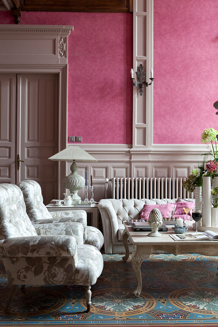 Floral armchairs and antique coffee table against dusky-pink wallpaper in traditional lounge