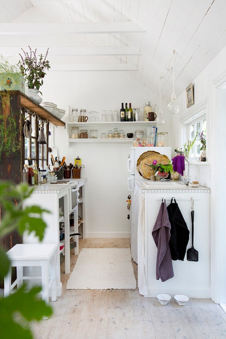 Kleine, funktionale Küche in weiss gestrichenem Holzhaus