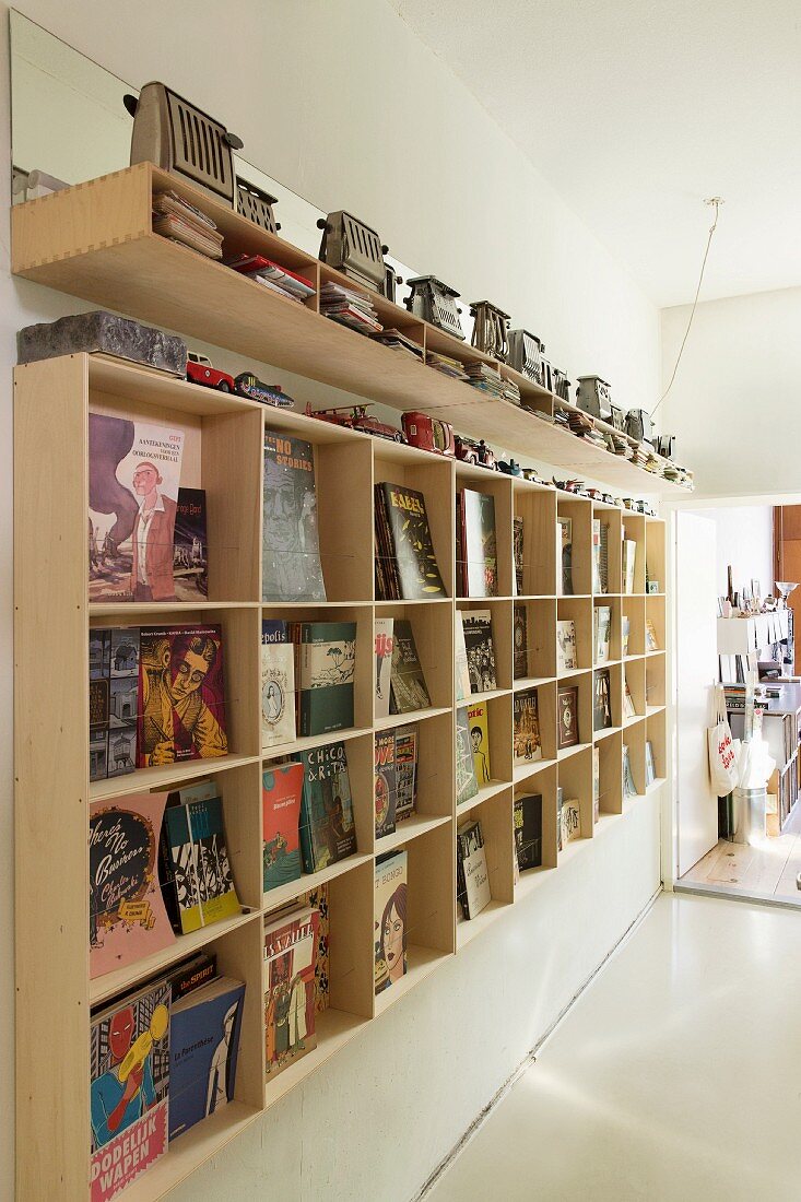 Selbstgebautes Regal aus Holz für Bücher, oberhalb auf Ablage Toaster Sammlung
