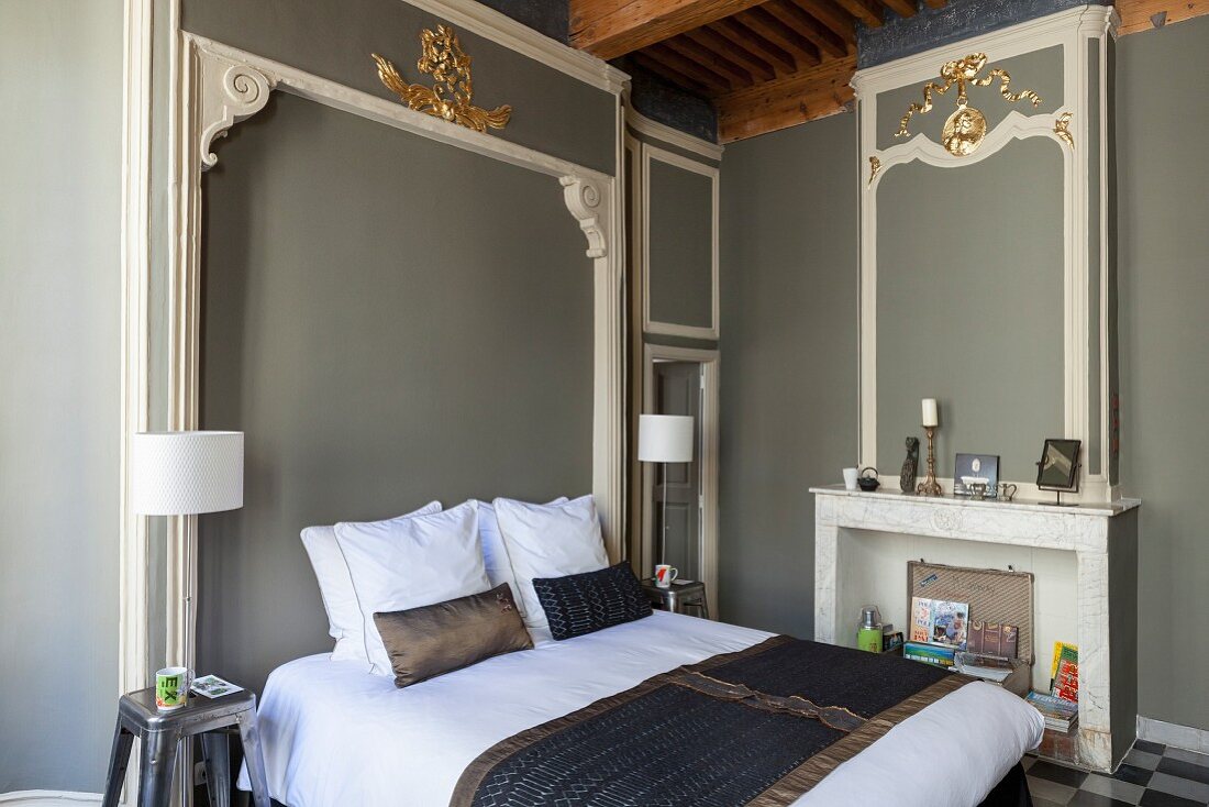 Doppelbett im Schlafzimmer mit Barock Motiven, Stuckelemente teilweise vergoldet an grau getönter Wand