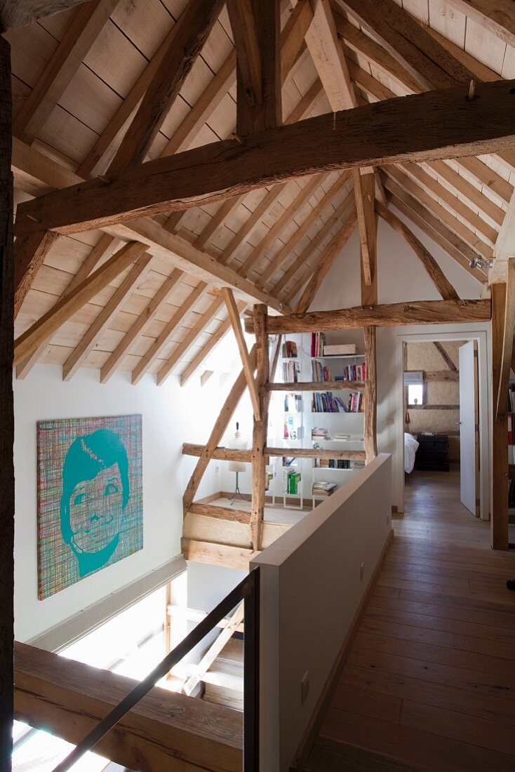 View of roof structure and open-plan sleeping area on gallery level of modernised farmhouse