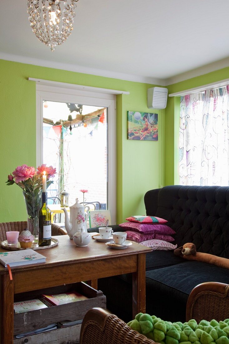 Coffee set and peonies on wooden table in living room with lime green walls