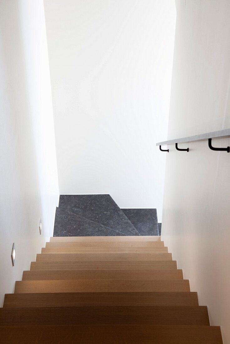 Wooden staircase leading to stone steps in narrow stairwell