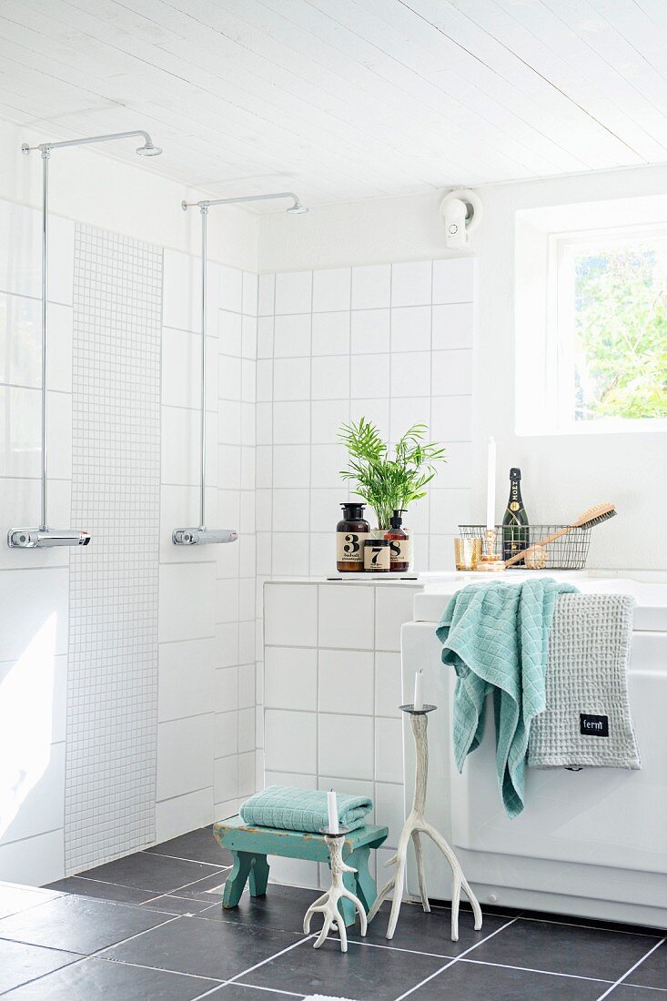 Badezimmerecke mit bodenebenem Duschbereich, neben teilweise sichtbarer Badewanne, graue Bodenfliesen in modernem Bad