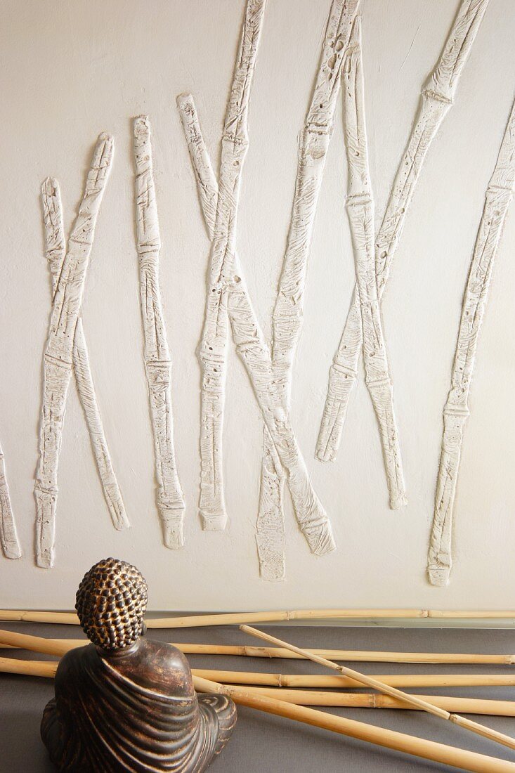 Bamboo canes, Buddha figurine and bamboo relief on wall