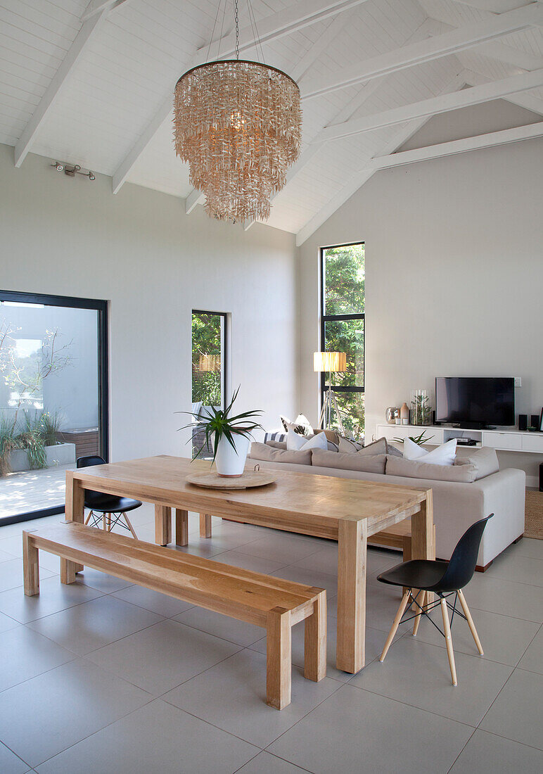 Wooden dining table and bench in bright, open-plan living area