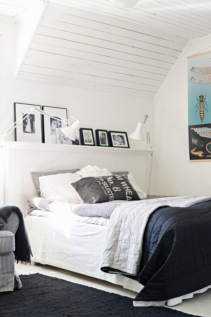 Doppelbett mit schwarz-weisser Tagesdecke im Dachzimmer mit weisser Holzverkleidung