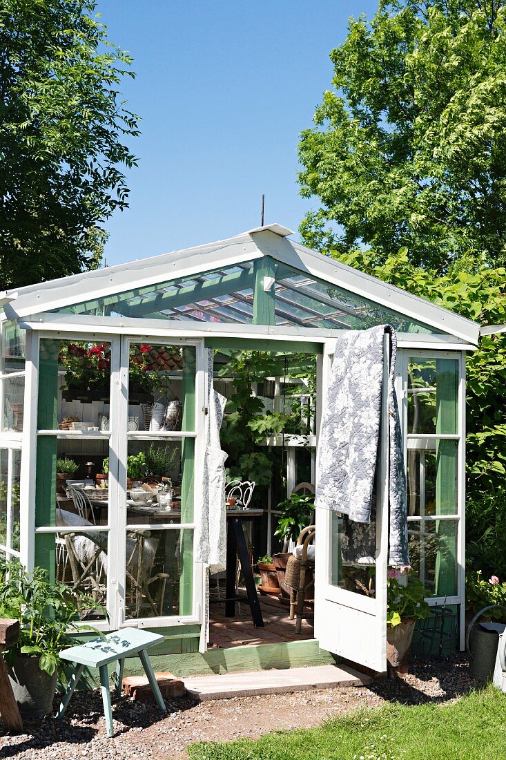 Greenhouse made from recycled materials in summery garden
