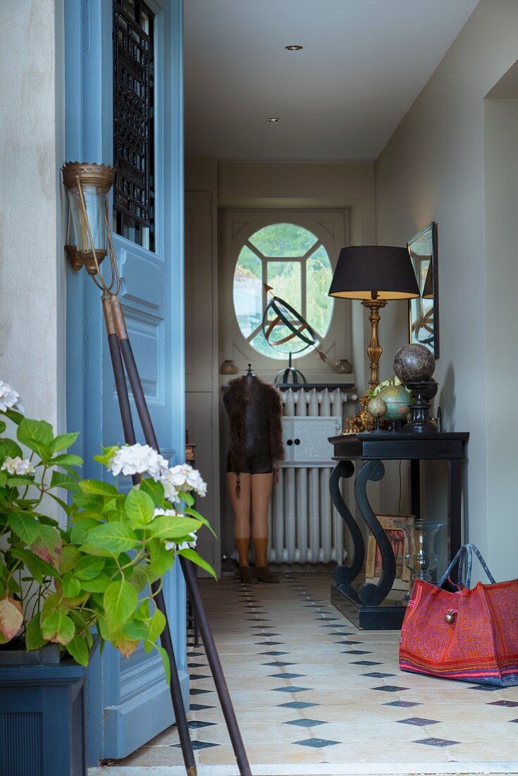 Blick durch offene Haustür in Landhaus-Flur mit schwarzem Konsolentisch