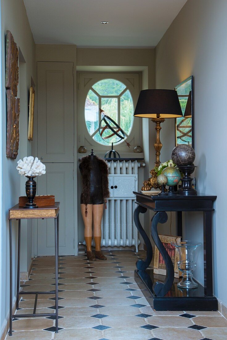 Antiker, schwarzer Konsolentisch mit Tischleuchte und nostalgische Schneiderpuppe in traditionellem Landhaus-Flur