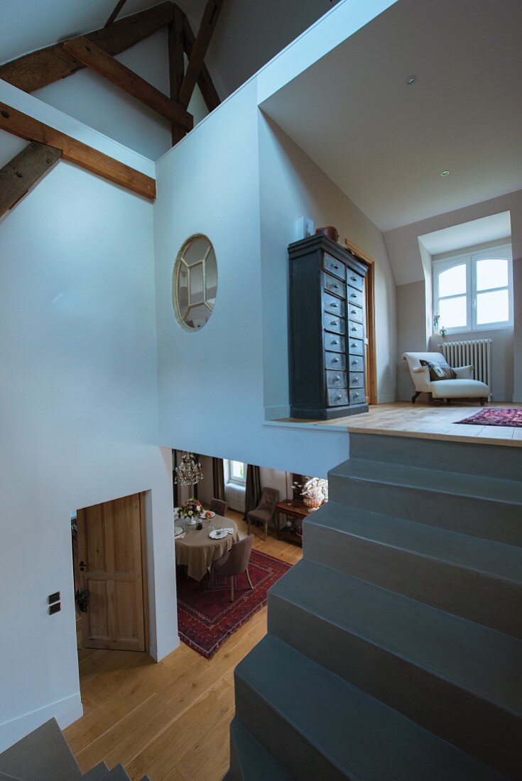 Concrete staircase without handrail leading to gallery in converted attic with view into lower storey