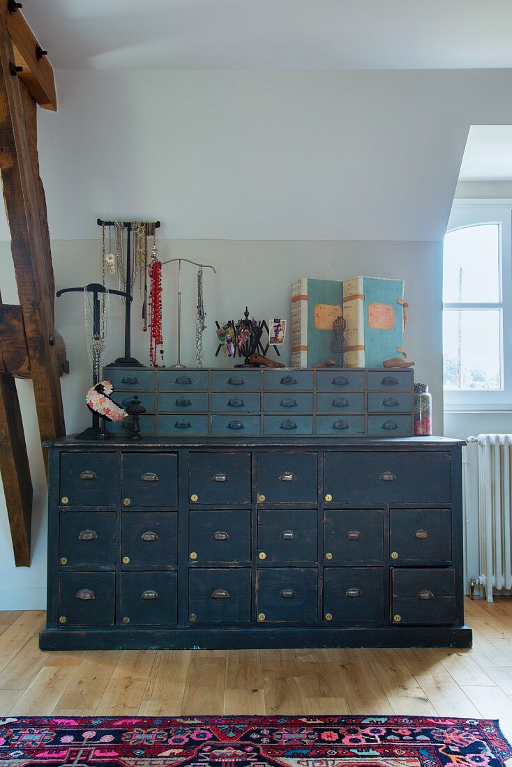 Graublaue Vintage Kommode mit Schubladen Aufsatz, Schmuckständer und nostalgische Stehordner im Dachgeschosszimmer