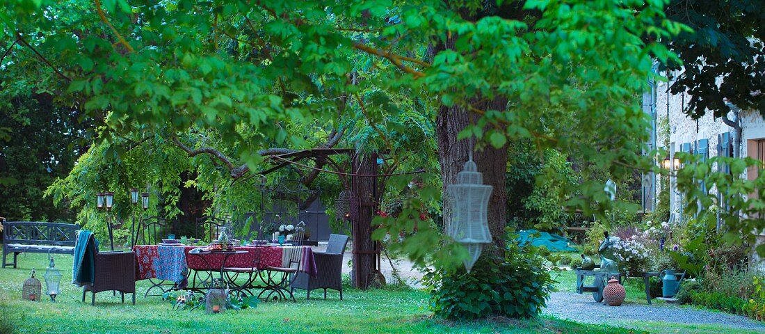 Gedeckter Tisch unter Kastanienbäumen vor ländlichem Anwesen