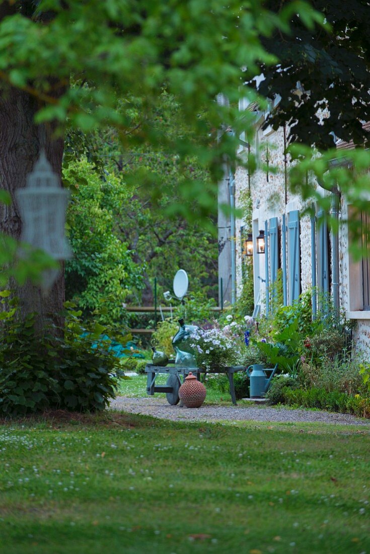 Idyllischer Gartenausschnitt mit Blick auf renoviertes Landhaus