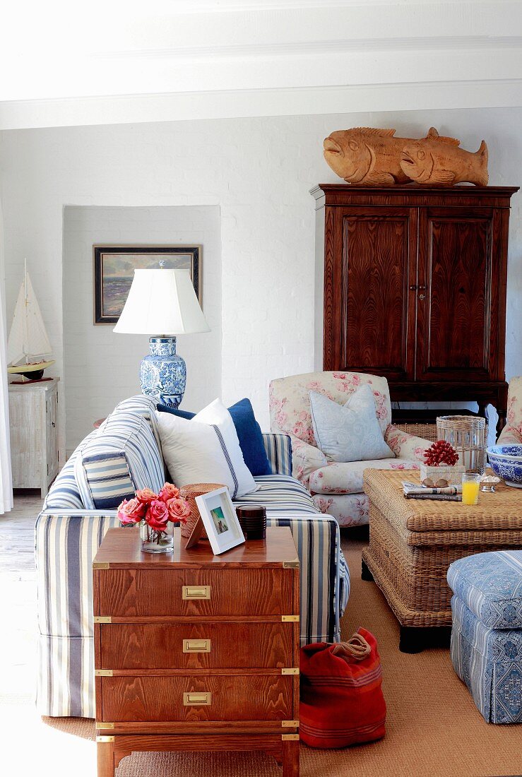 Romantisches Wohnzimmer mit verschiedenen Polstermöbeln und antikem Holzschrank