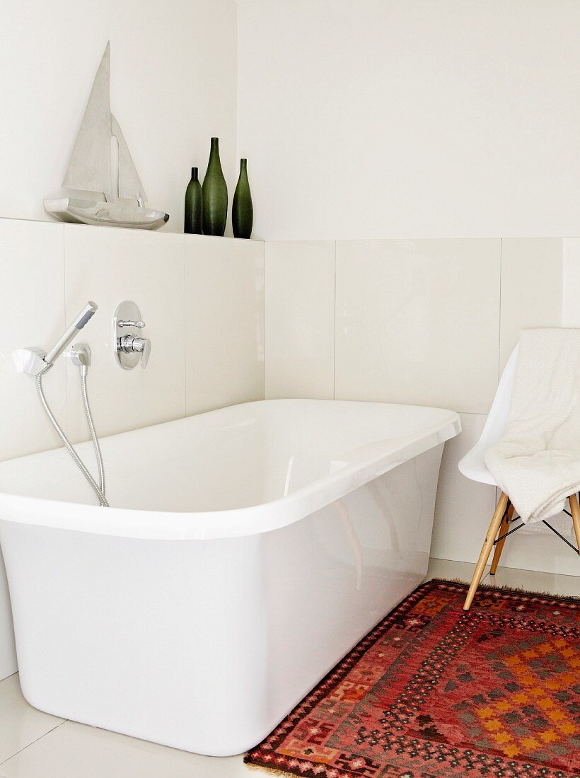 Freistehende weiße Badewanne in hellem Badezimmer mit Teppich