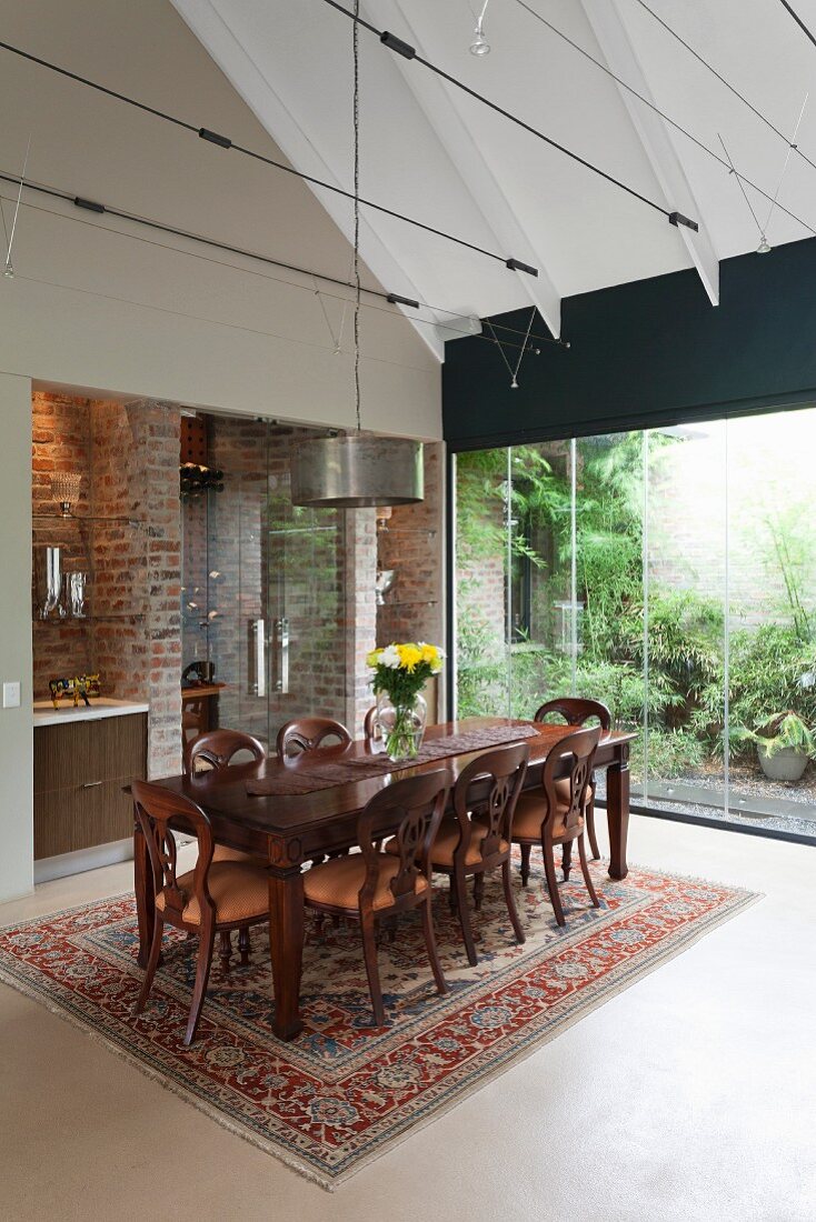 Eleganter Esstisch auf Orientteppich in hohem, modernen Wohnraum