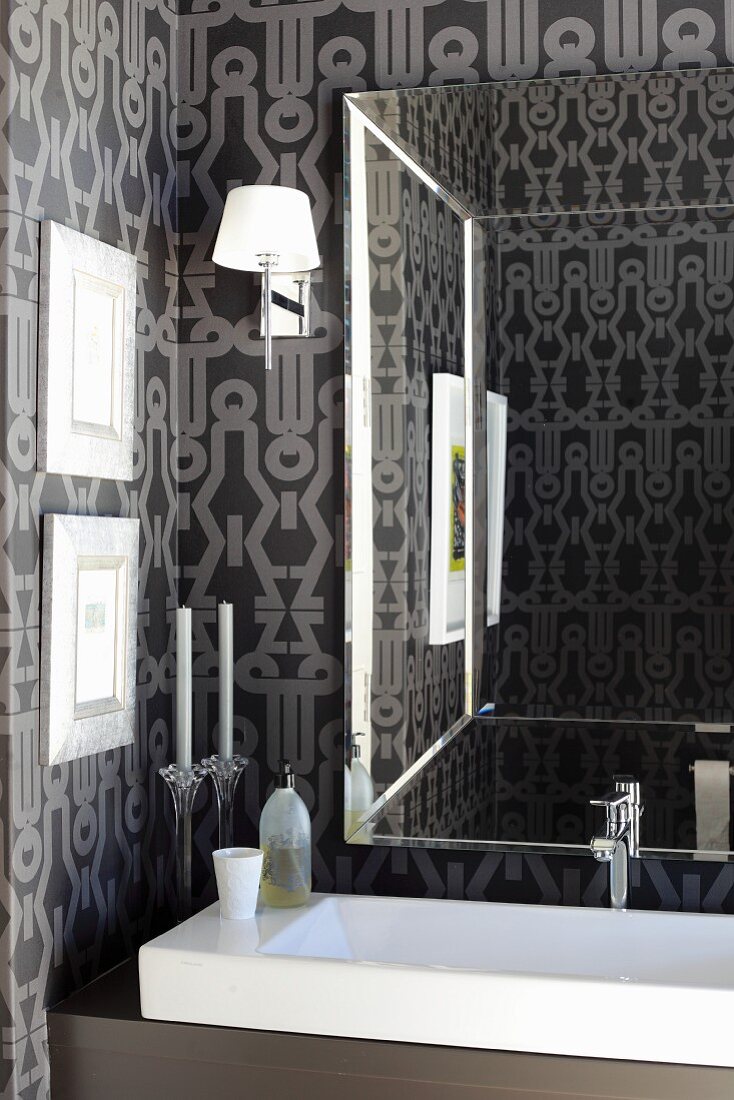 Mirror in elegant bathroom with expressive wallpaper and long designer sink