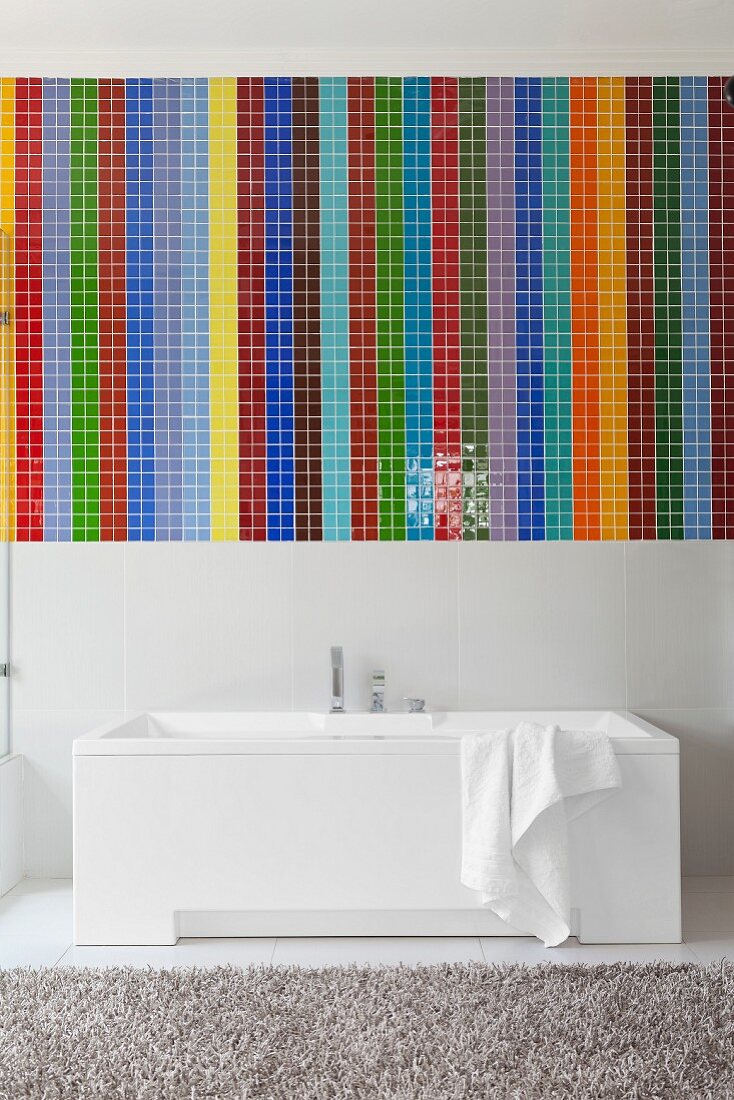 Mosaic of colourful wide stripes above white designer bathtub