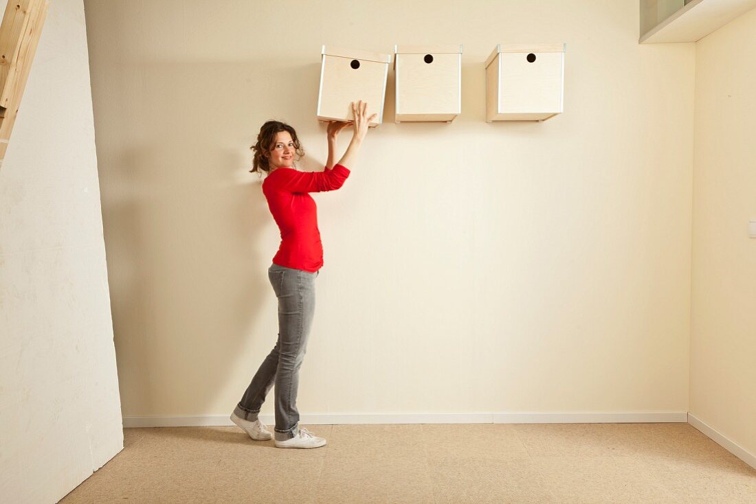 Woman holding box next to storage boxes hung on wall