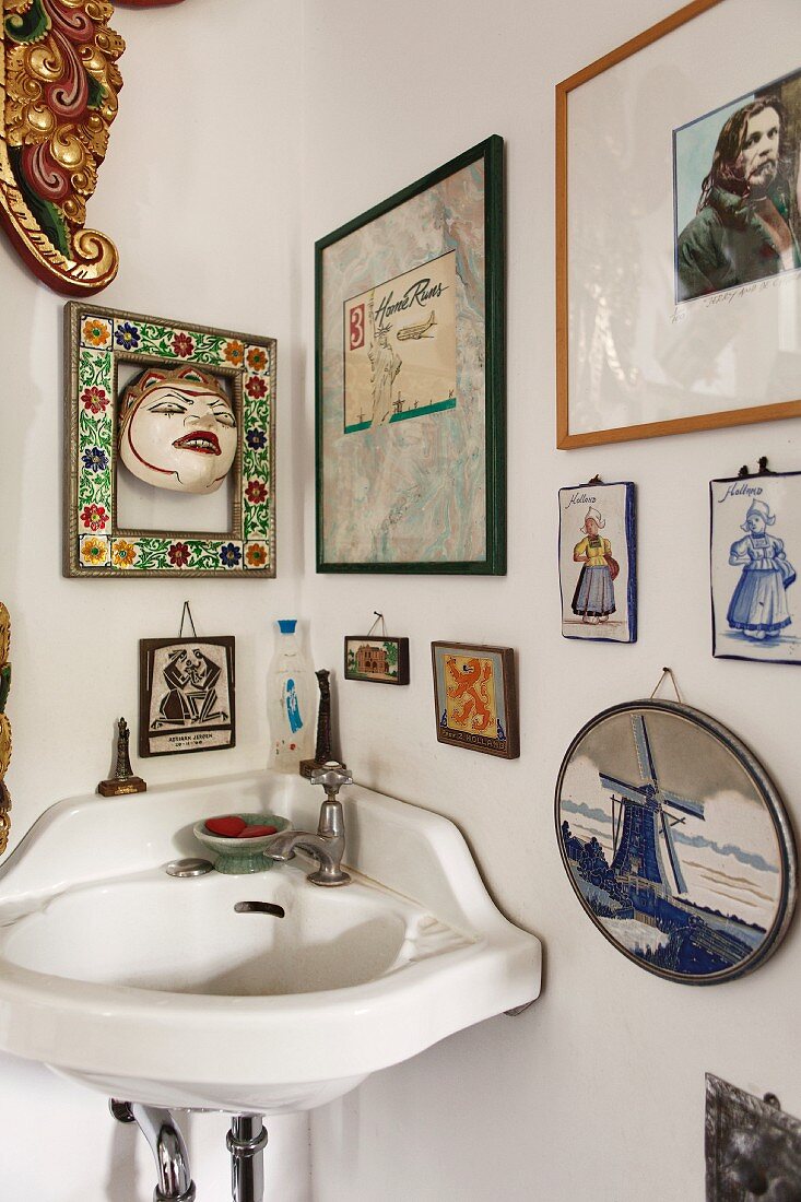 Corner sink below various pictures and ornaments on wall