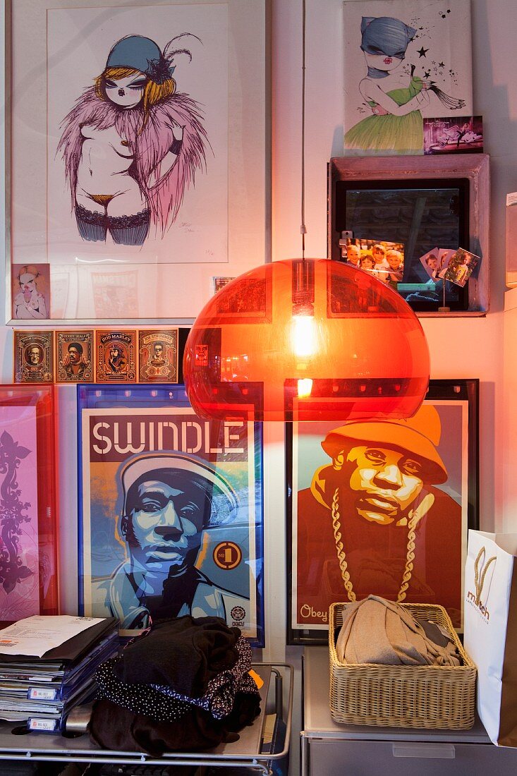 Orange, plastic, retro pendant lamp in front of gallery of pictures