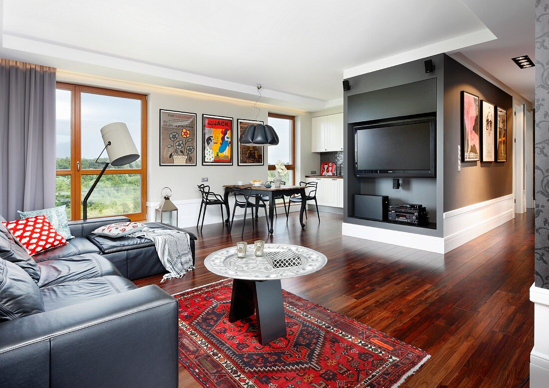 Edelholz-Parkettboden in offenem Wohnraum, Ledersofa und Beistelltisch auf Orientteppich in Loungebereich mit Fernseher