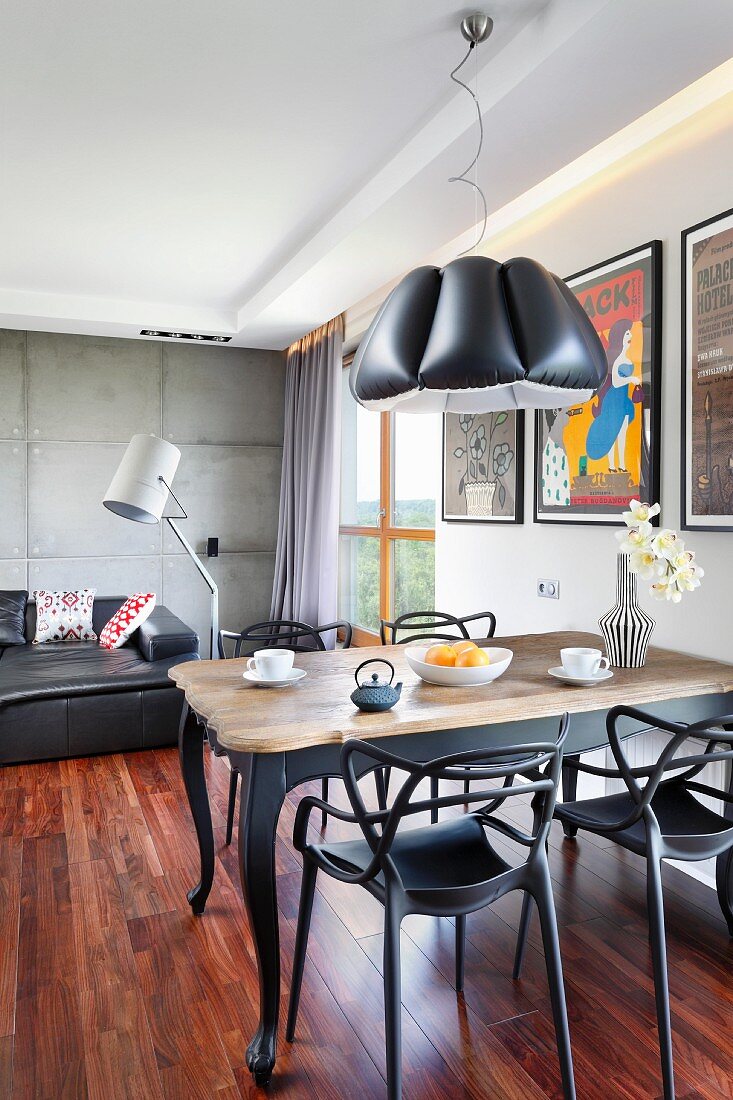 Open-plan interior in eclectic style; modern lounge with standard lamp and exposed concrete wall