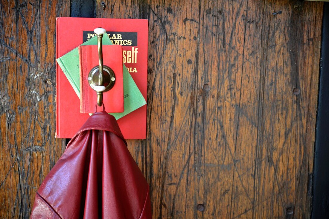 DIY-Garderobe aus Büchern und Kleiderhaken an rustikaler Holzwand