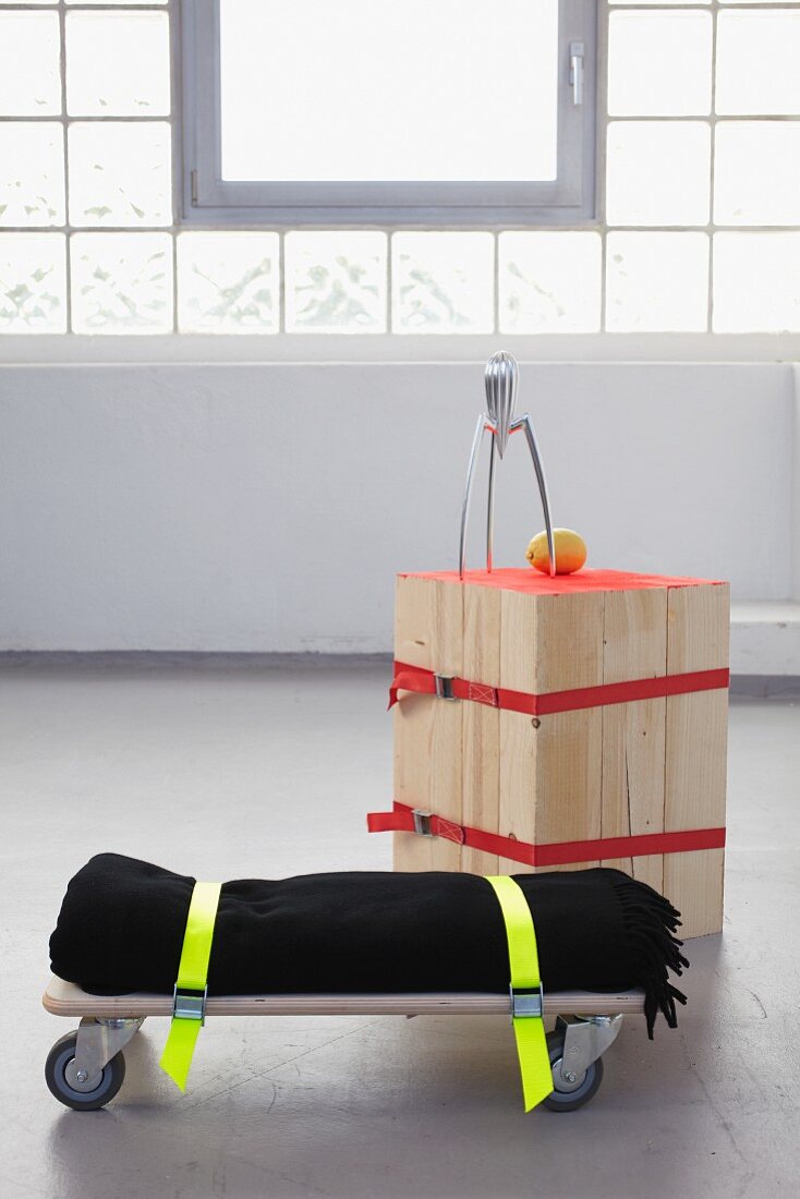DIY stool made from wooden slats and seat made from blanket strapped to trolley