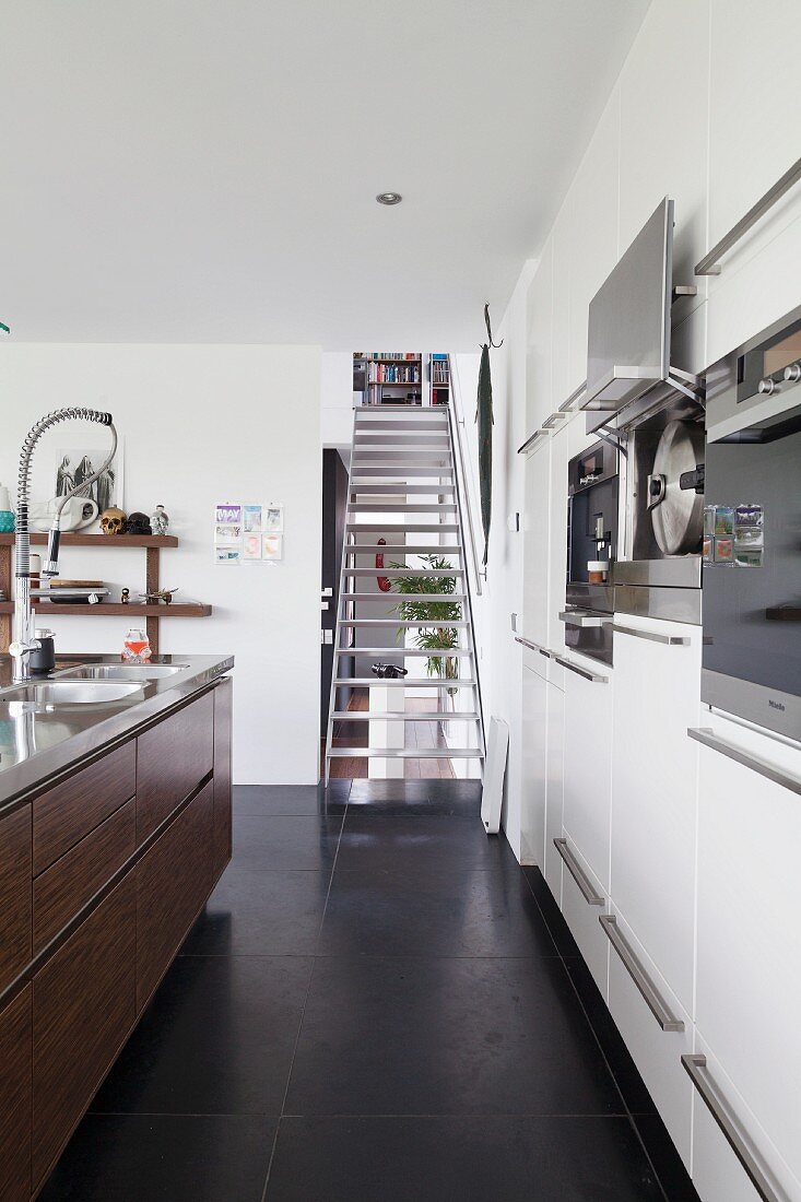 Metal staircase in designer kitchen with black, tiled floor