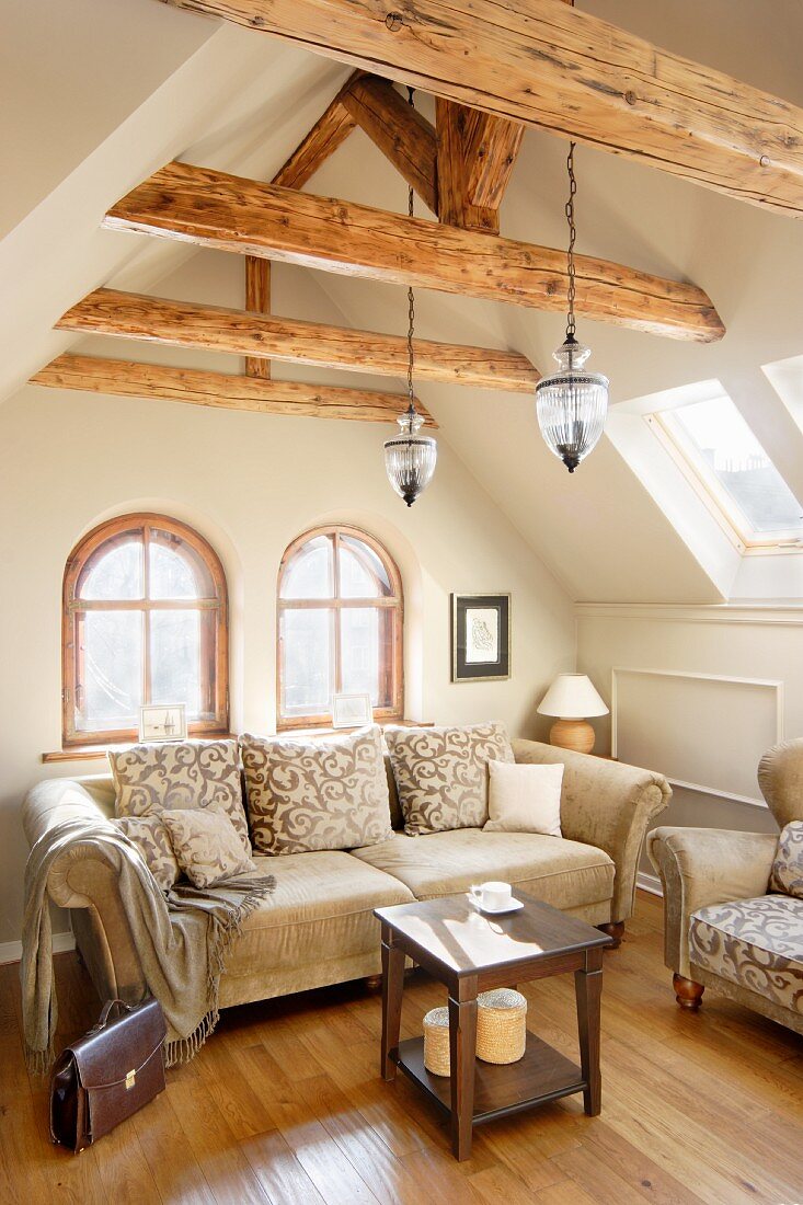 Sitzecke mit traditionellen Sofas unter alten Holzbalken im Dachgeschoss