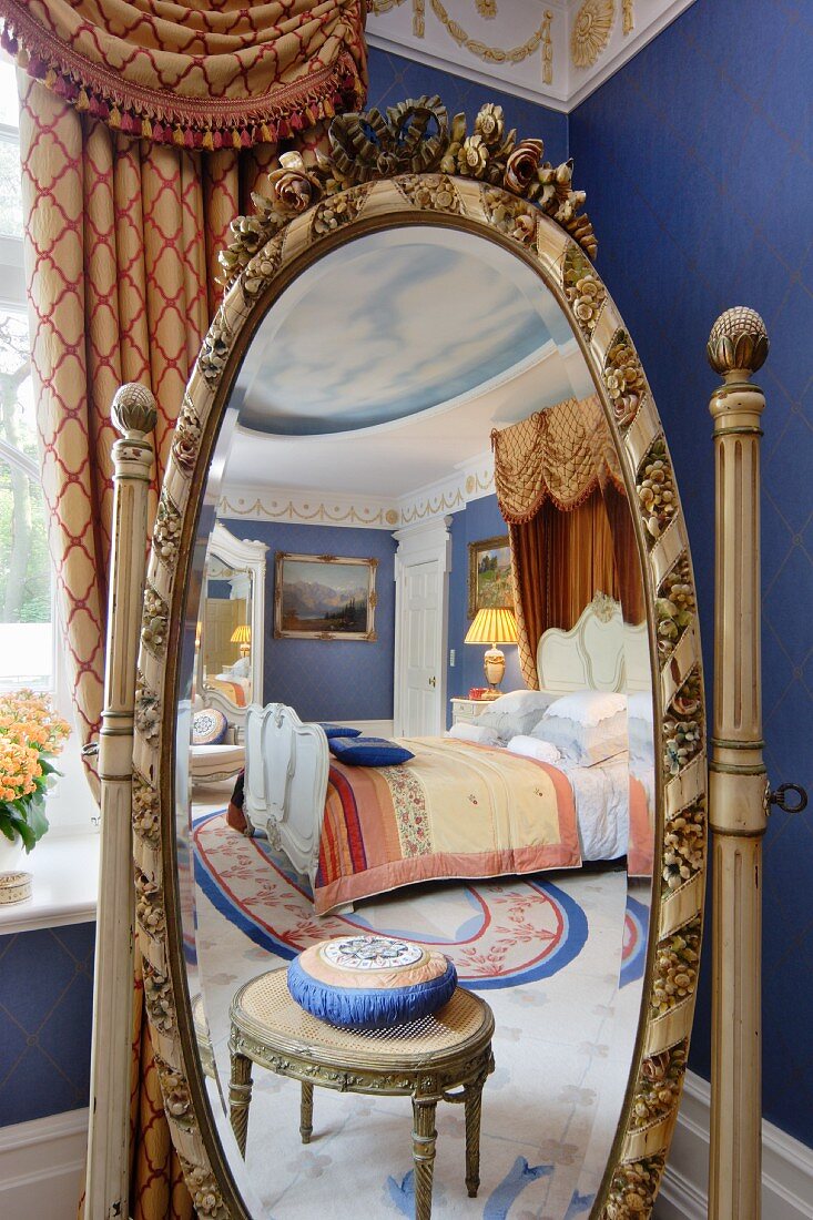 In ovalem Standspiegel mit geschnitztem Rahmen, reflektierter antiker Schemel und luxuriöses Doppelbett mit Baldachin
