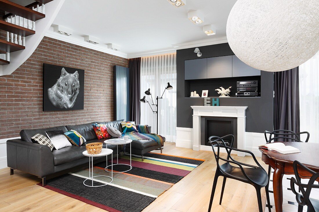 Schwarze Möbel, grafische Muster und eine Ziegelwand mit Tiermotiv in modernem Wohnzimmer