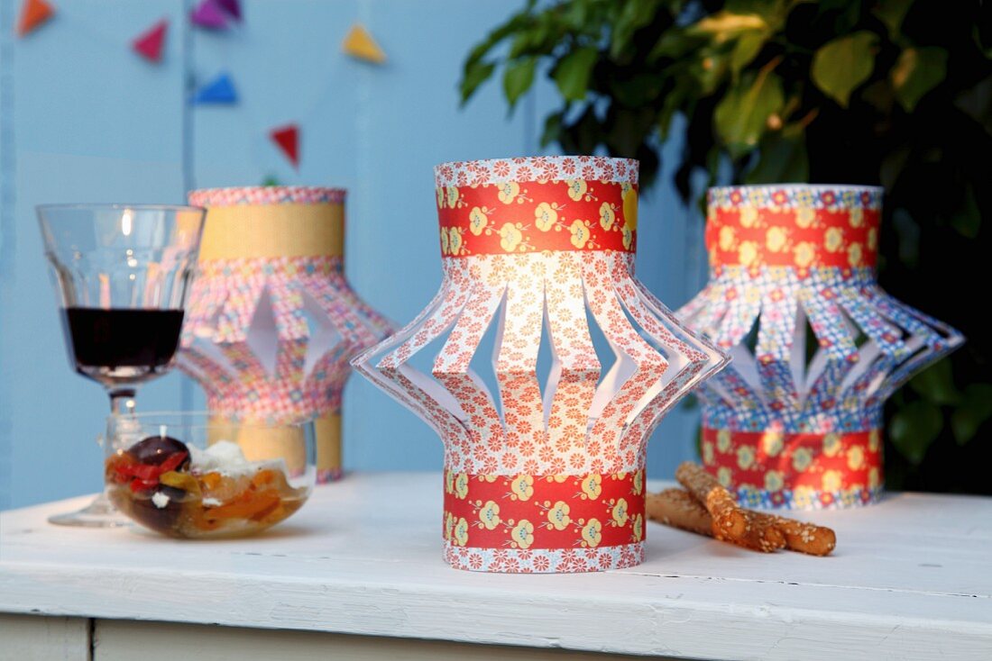 Lantern-style lampshades made from brightly patterned, folded and slit paper on tealight holders