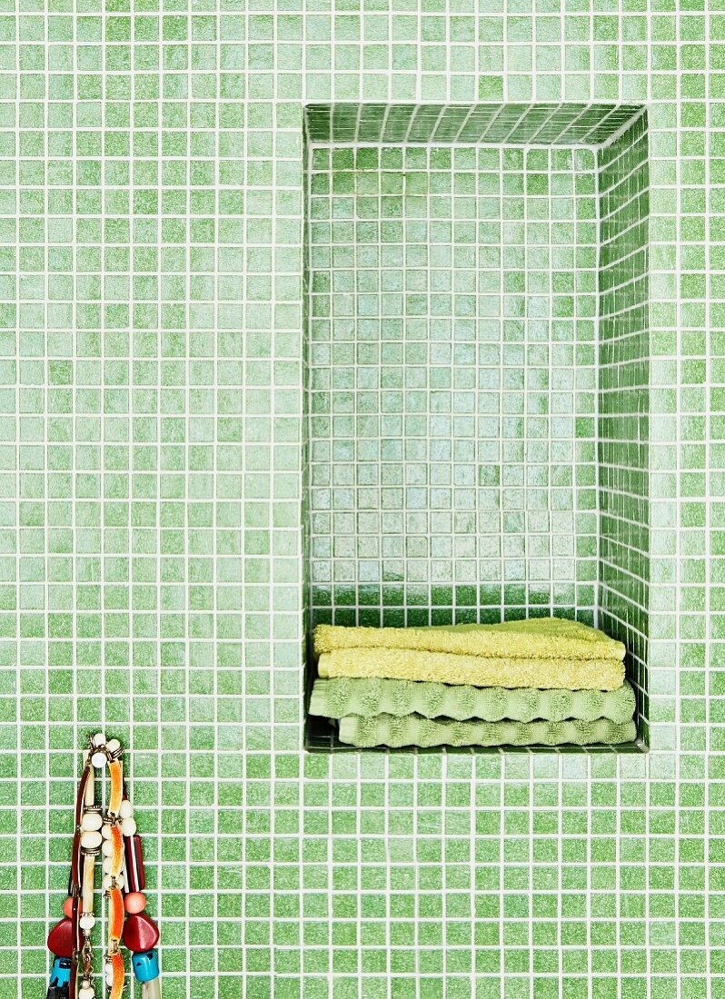 Bathroom with green mosaic tiles and towels in niche