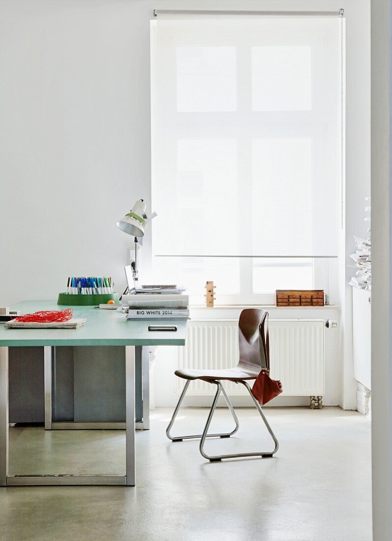 Moderner Schreibtischplatz mit Retro Stuhl neben Fenster mit weißem Rollo